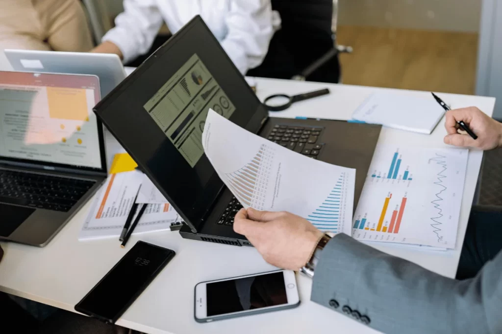 Hands holding printed business reports with sales and revenue metrics.