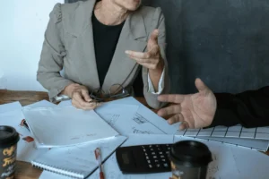 Business professionals discussing reports with calculator on desk.