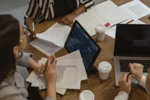 Group discussion with graphs, reports, and laptops.