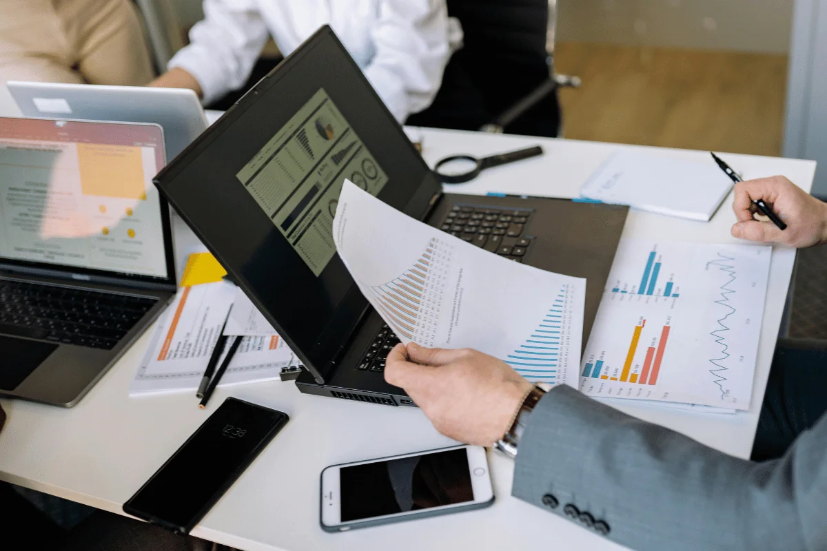 Hands holding printed business reports with sales and revenue metrics.