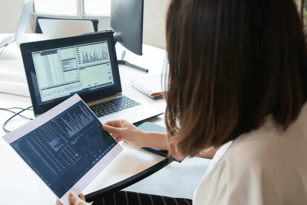 Professional reviewing company performance data on paper and computer.