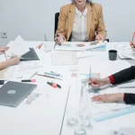 A diverse group of professionals collaborates around a conference table, analyzing documents and discussing strategies.