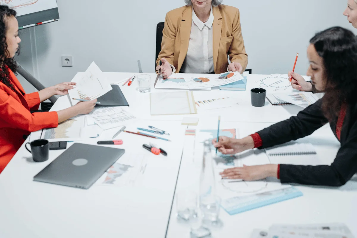 A diverse group of professionals collaborates around a conference table, analyzing documents and discussing strategies.