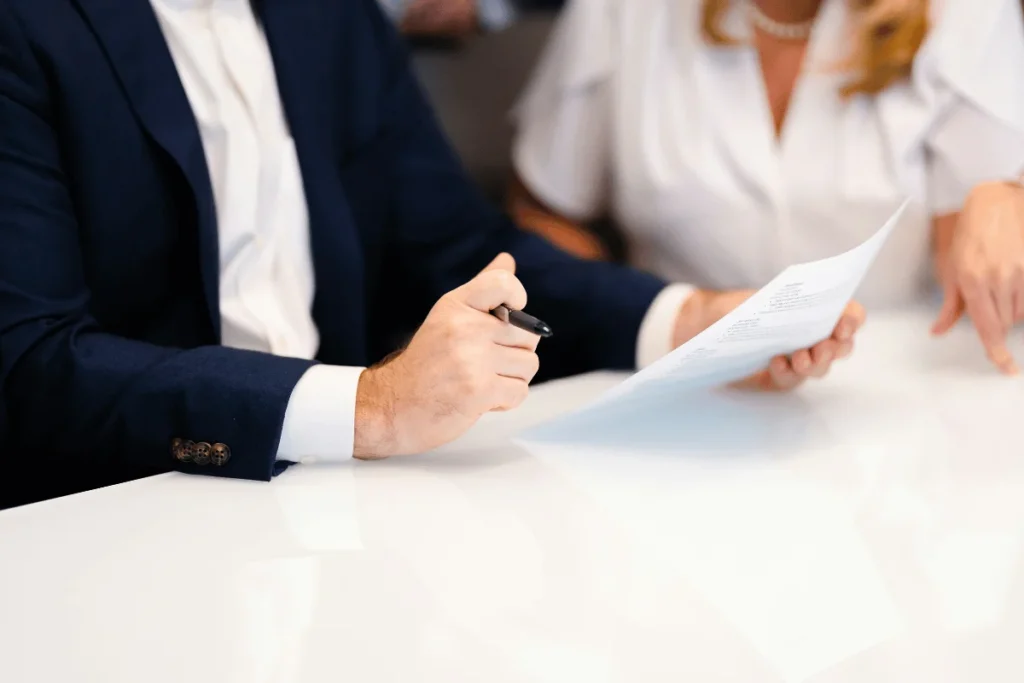 Business partners reviewing contract papers at a white office table.