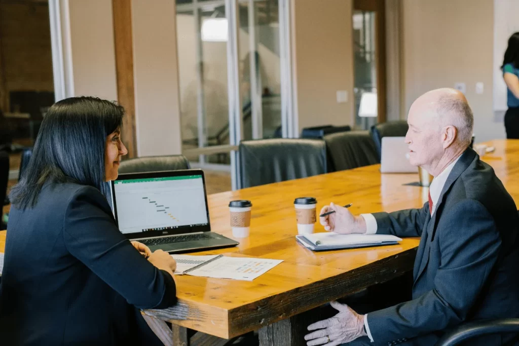 Businesswoman and businessman discussing finance in office meeting.