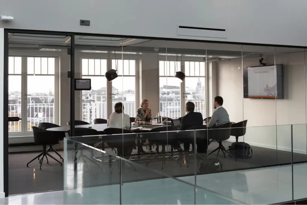 Group of executives in a boardroom with city views in the background.