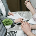 Colleagues discussing paperwork during a professional meeting.