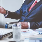 Business professional in suit discussing financial strategy at desk.