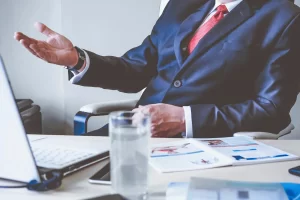 Business professional in suit discussing financial strategy at desk.