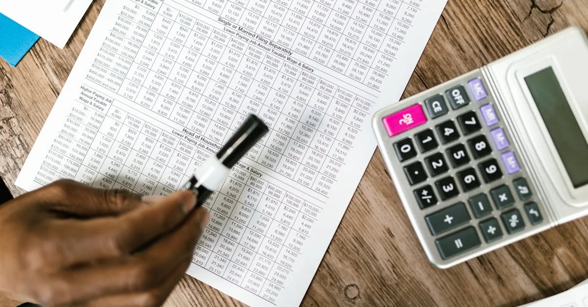 Hand holding pen over tax forms with calculator on wooden desk showing alternative minimum tax Canada calculations.
