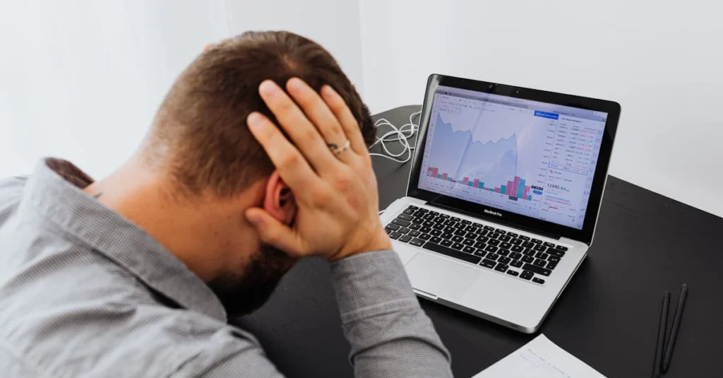  Frustrated professional at desk with laptop showing declining analytics charts, representing lost high tech M&A integration.
