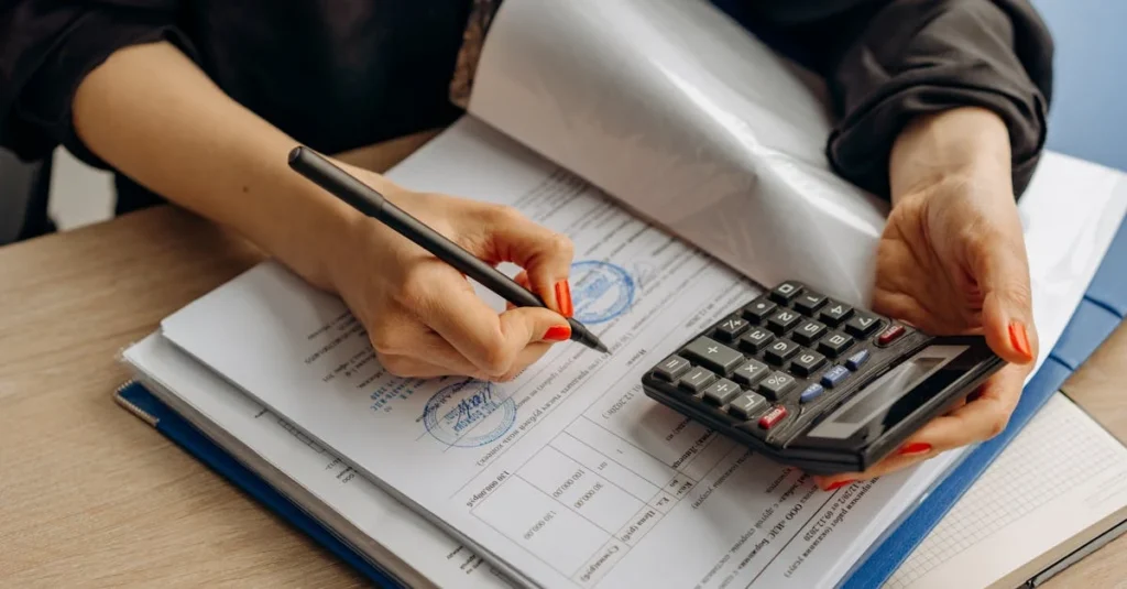 Hands calculating with calculator and pen on financial documents.