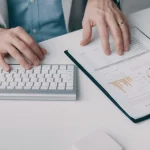 Professional reviewing data charts while working on computer.