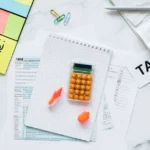 Tax documents, calculator, and sticky notes displaying new AMT rules Canada information on marble desk surface.