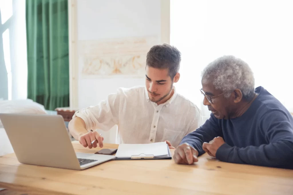 Advisor and client reviewing paperwork with a laptop.