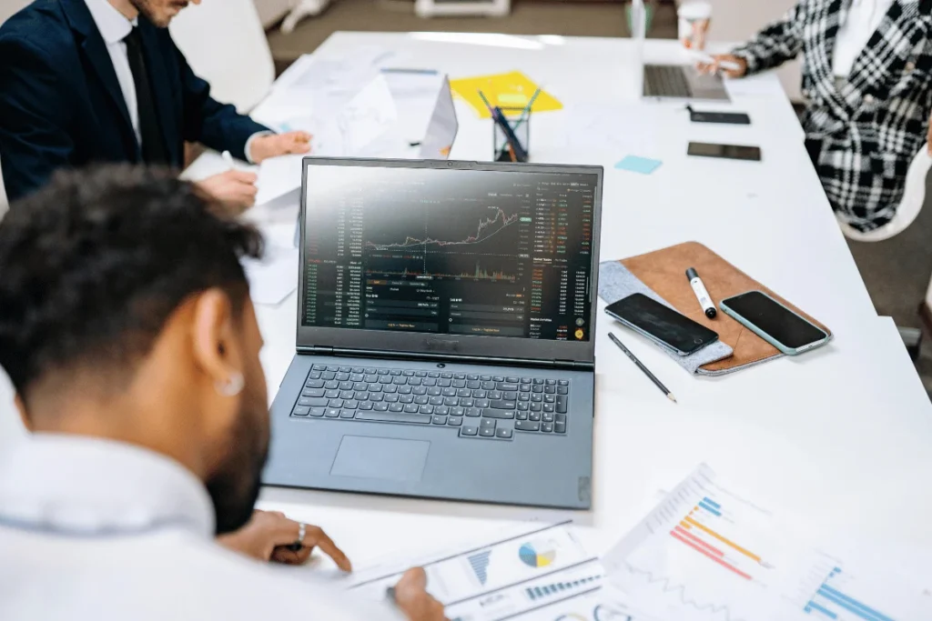 Business team analyzing stock market data on laptop screen.