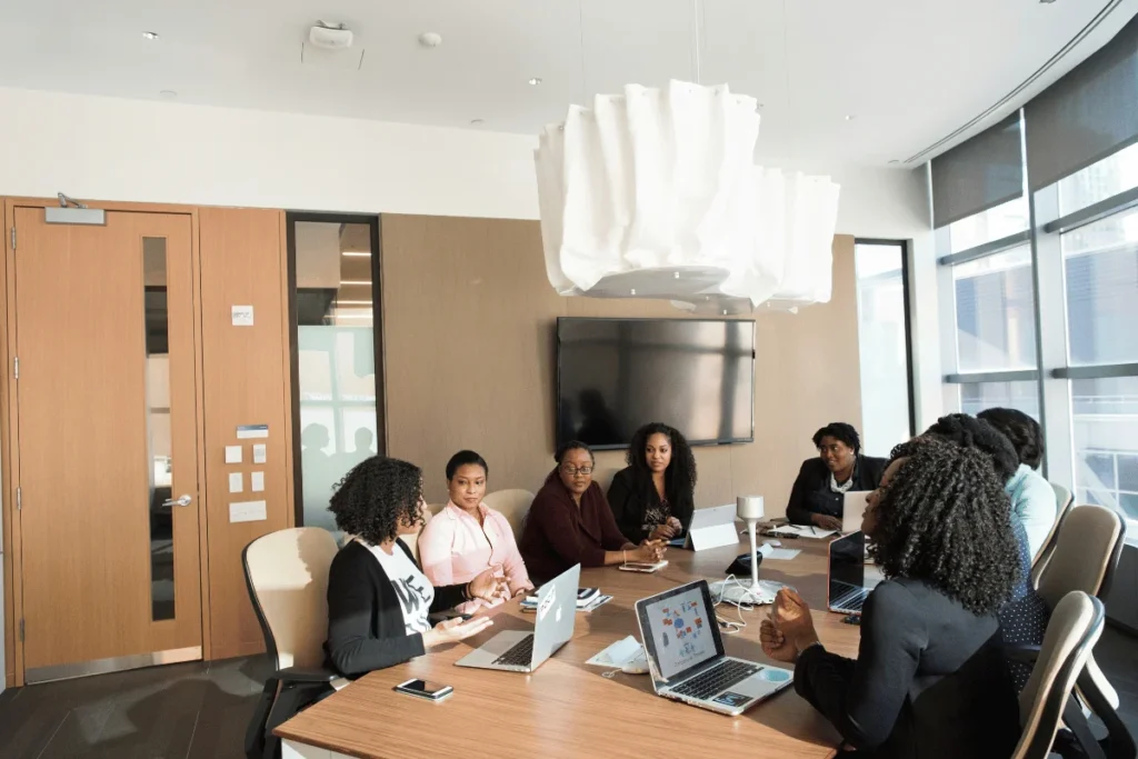 Office meeting scene with team members discussing ideas at conference table.