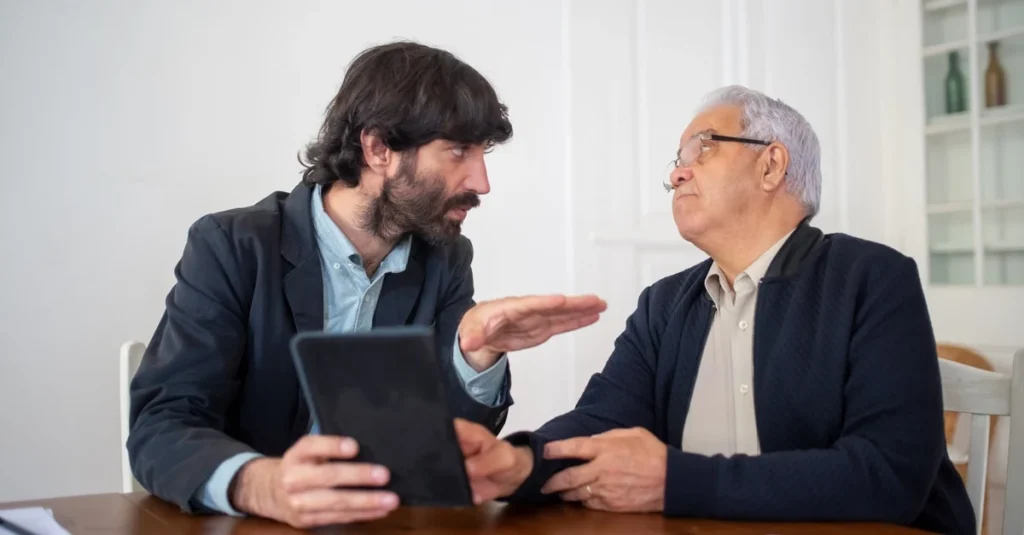 Two business advisors review tablet discussing sell business Ontario strategy at wooden office table.