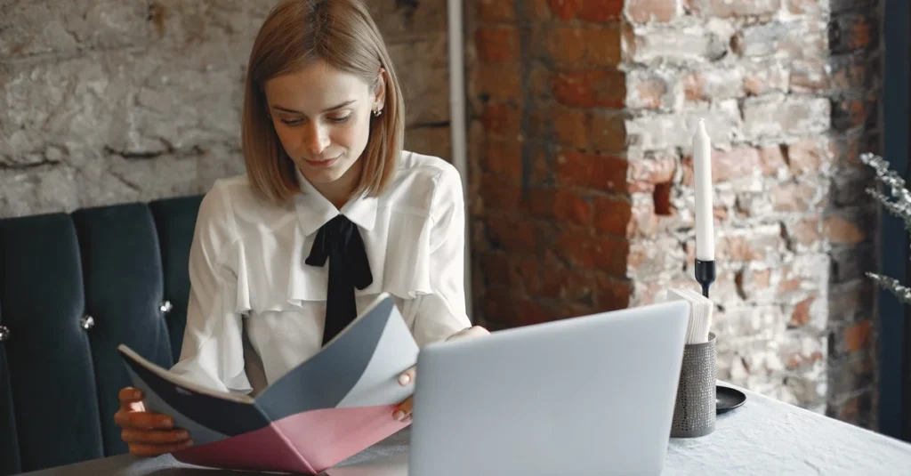 Woman reviewing business documents while working on laptop at desk in industrial Toronto loft space.